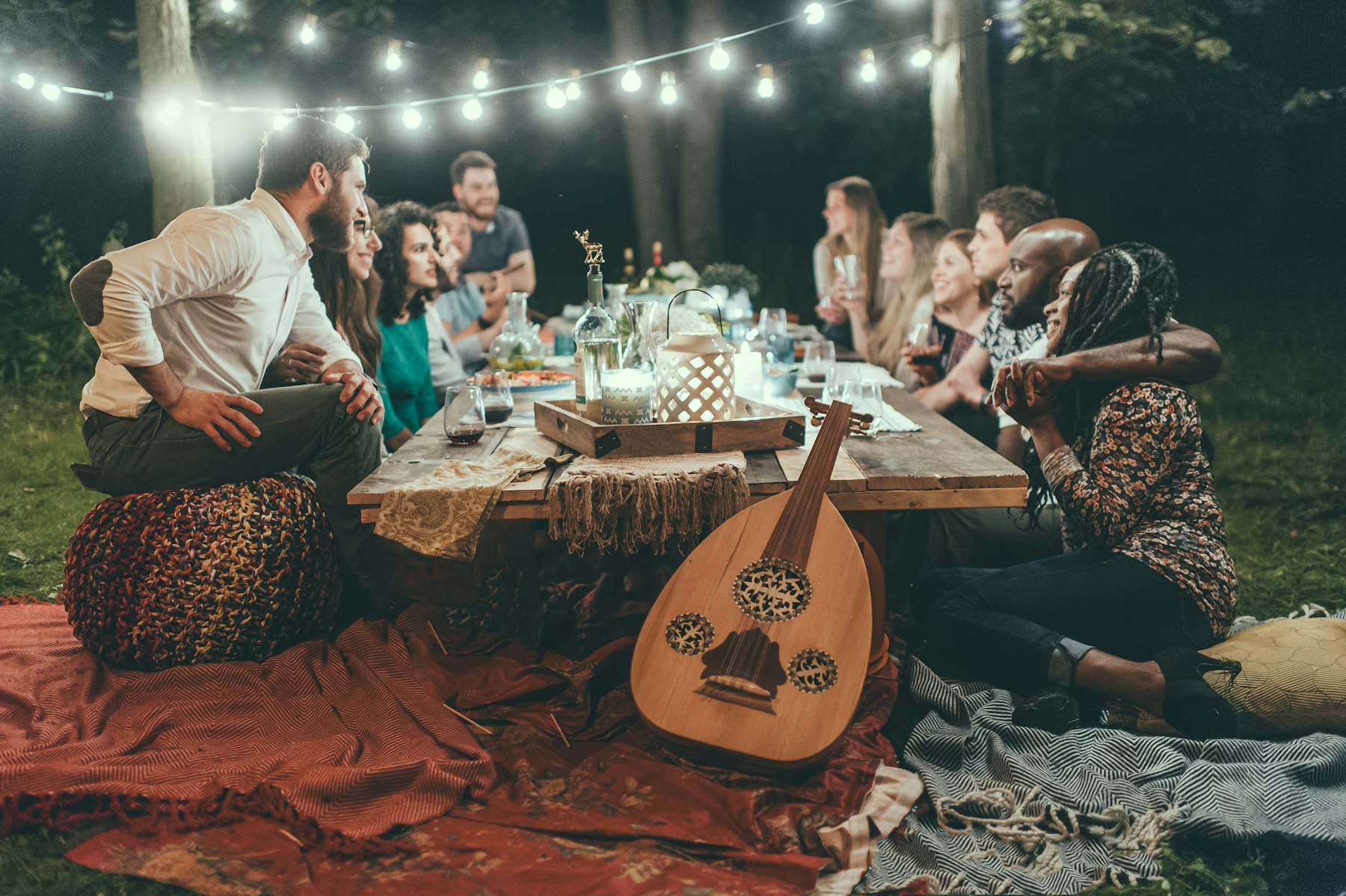 Ten guests around a low candlelit table under string lights